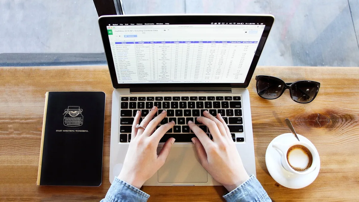 Restaurant manager processing staff payroll on a laptop in the back office