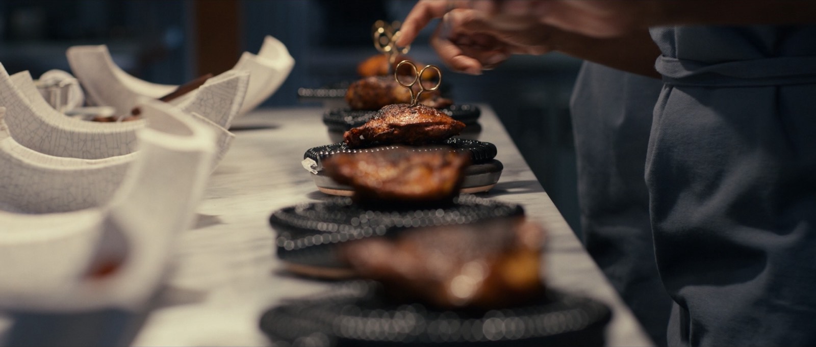 A chef garnishing plated dishes on a restaurant kitchen line.