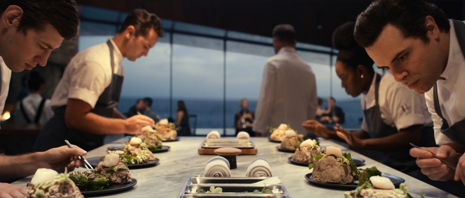A team of chefs plating dishes along the pass during service.