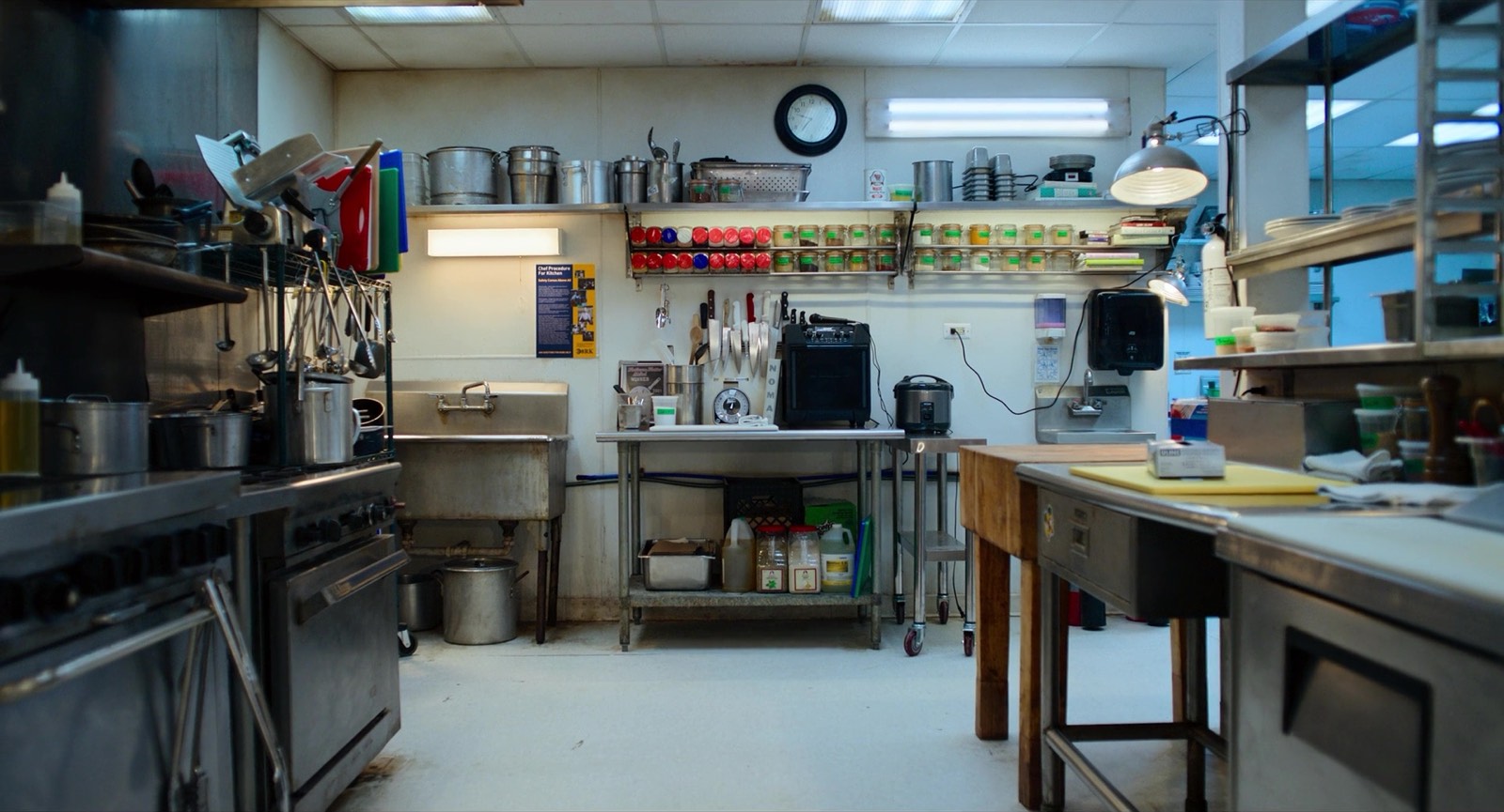 A back-of-house restaurant kitchen lined with stocked storage shelves and prep stations.